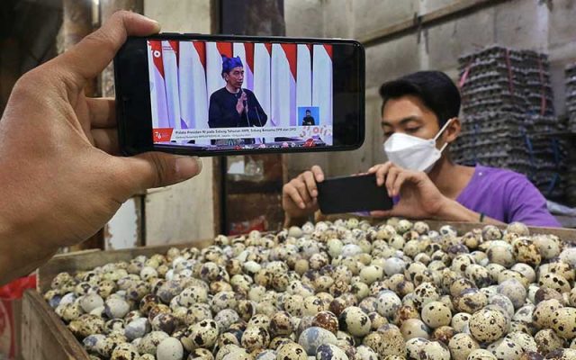 Pedagang menyaksikan Presiden Joko Widodo menyampaikan pidato dalam Sidang Tahunan MPR Tahun 2021 melalui live streaming di Jakarta, Senin (16/8/2021). Dalam kesempatan tersebut, Jokowi menyampaikan sejumlah poin penting terkait kesehatan dan penanganan pandemi Covid-19. Bisnis - Eusebio Chrysnamurti