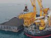 Aktivitas pemindahan muatan batu bara dari tongkang ke kapal induk dengan floating crane. - indikaenergy.co.id