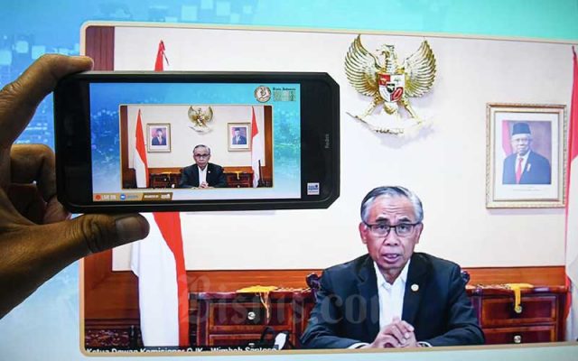 Layar menampilkan Ketua Dewan Komisioner OJK Wimboh Santoso saat berbicara di acara Bisnis Indonesia Business Challenges 2022 secara virtual di Jakarta, Rabu (15/12/2021). Bisnis - Abdurachman