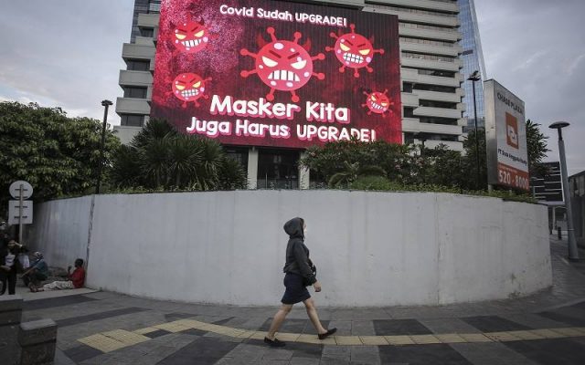 Warga berjalan di depan videotron mengenai protokol kesehatan di kawasan Jalan Jenderal Sudirman, Jakarta, Senin (13/9/2021). Pemerintah memutuskan untuk terus melanjutkan Pemberlakuan Pembatasan Kegiatan Masyarakat (PPKM) Level 2-4 di Jawa-Bali hingga 20 September 2021 untuk menekan penyebaran Covid-19. ANTARA FOTO - Dhemas Reviyanto